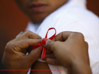 A red ribbon is put on the sleeves of a man by his friend to show support for people living with HIV.Reuters