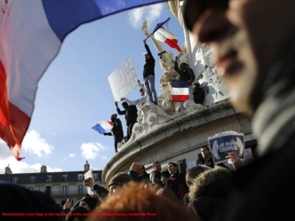 Demonstrators wave flags on the monument at the center of Republique Square. Associated Press