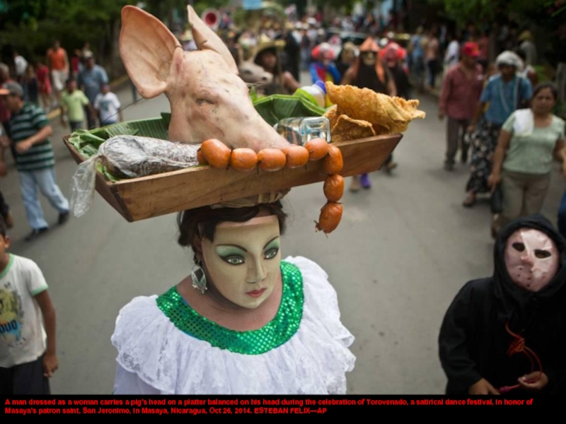 A man dressed as a woman carries a pig's head on