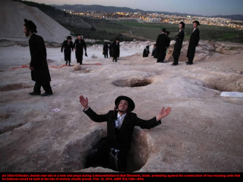 An Ultra-Orthodox Jewish man sits in a hole and prays during