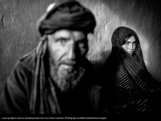 A young Afghan woman standing beside her much older husband. (Photograph by Majid Saeedi/Getty Images)