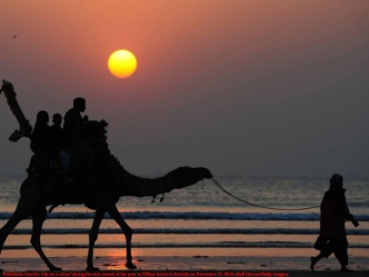 Pakistanis tourists ride on a camel during the last sunset of the year at Clifton beach in Karachi on December 31, 2014. (Asif Hassan/Getty Images)